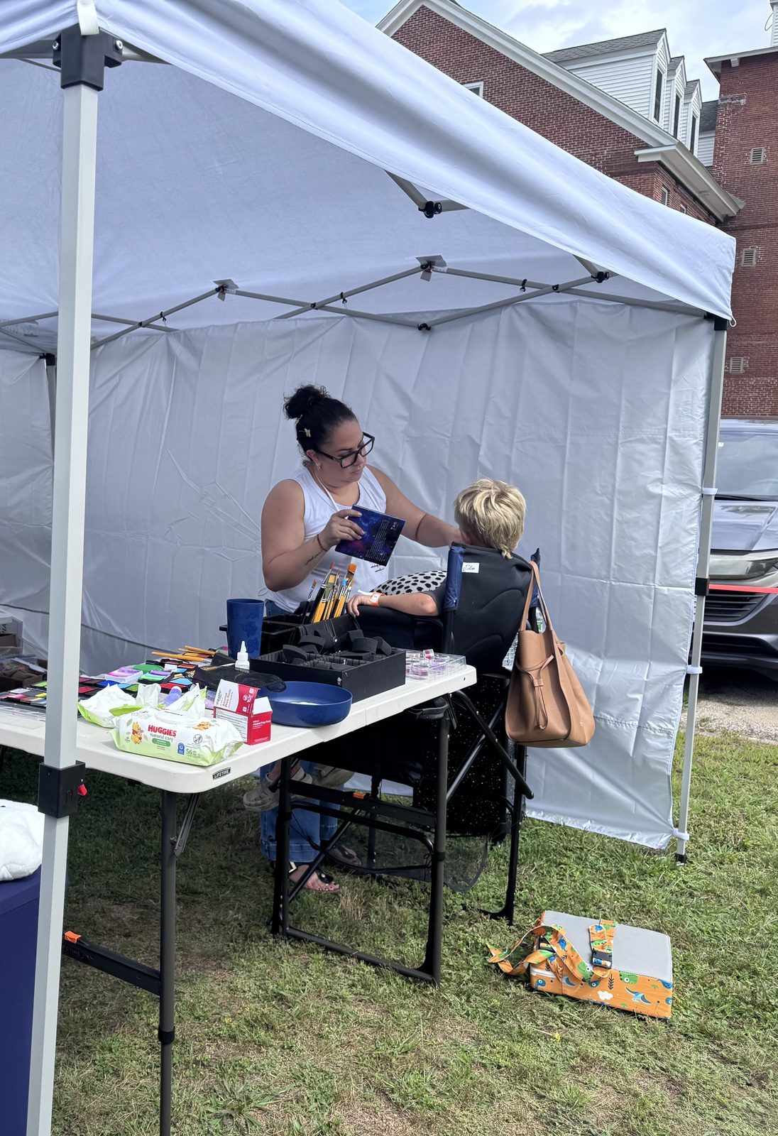 A face painting artist at work under a tent