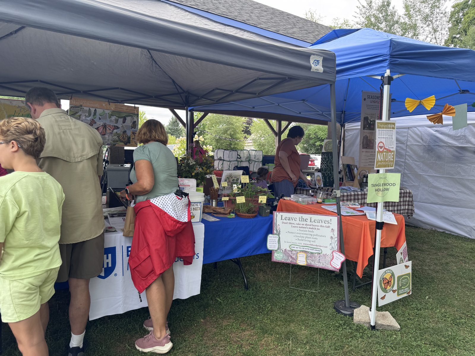 Visitors browsing vendor tables including a conservation display
