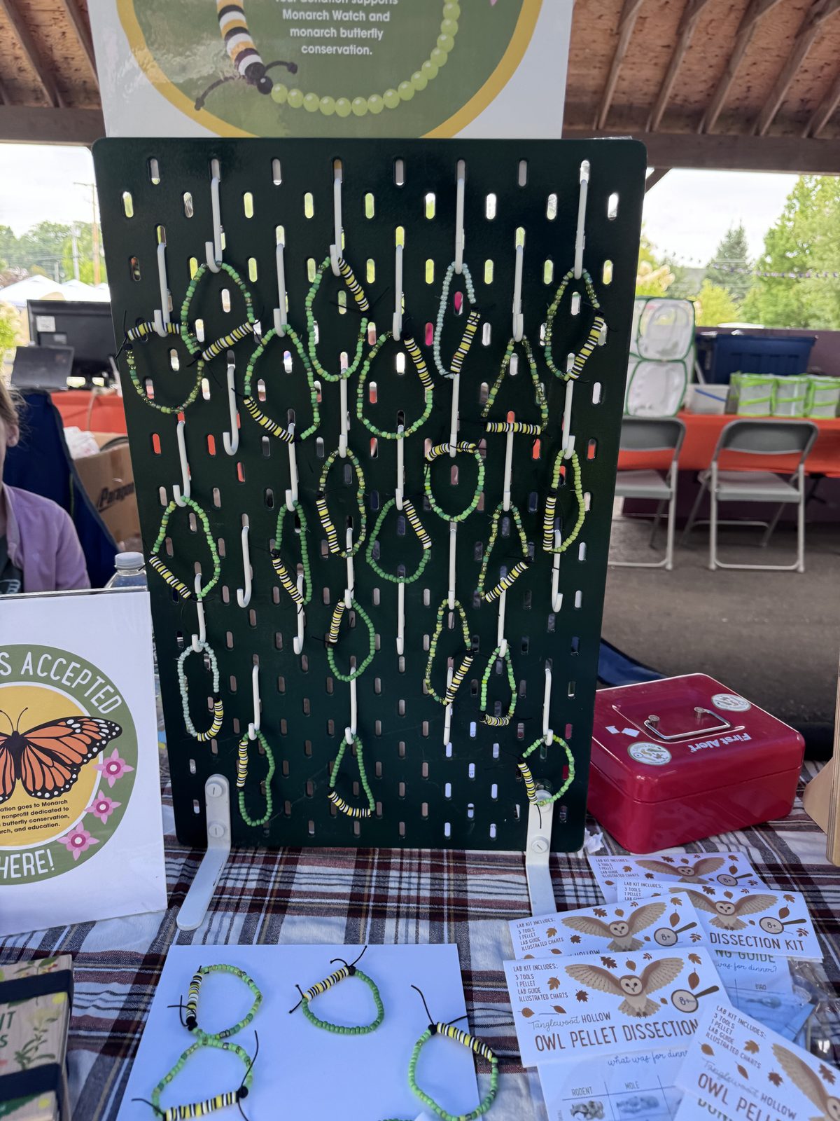 Pegboard display of handmade beaded monarch caterpillar bracelets