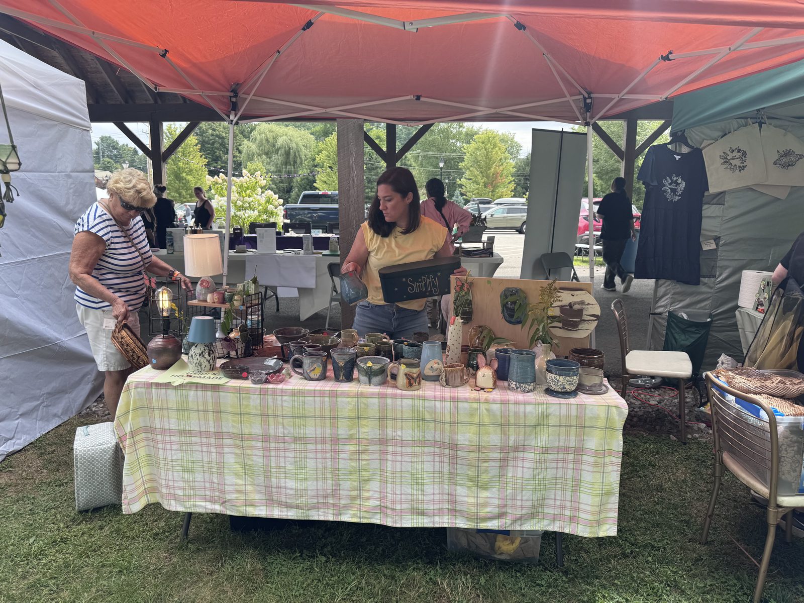 Vendor booth with pottery and plants, helping a customer