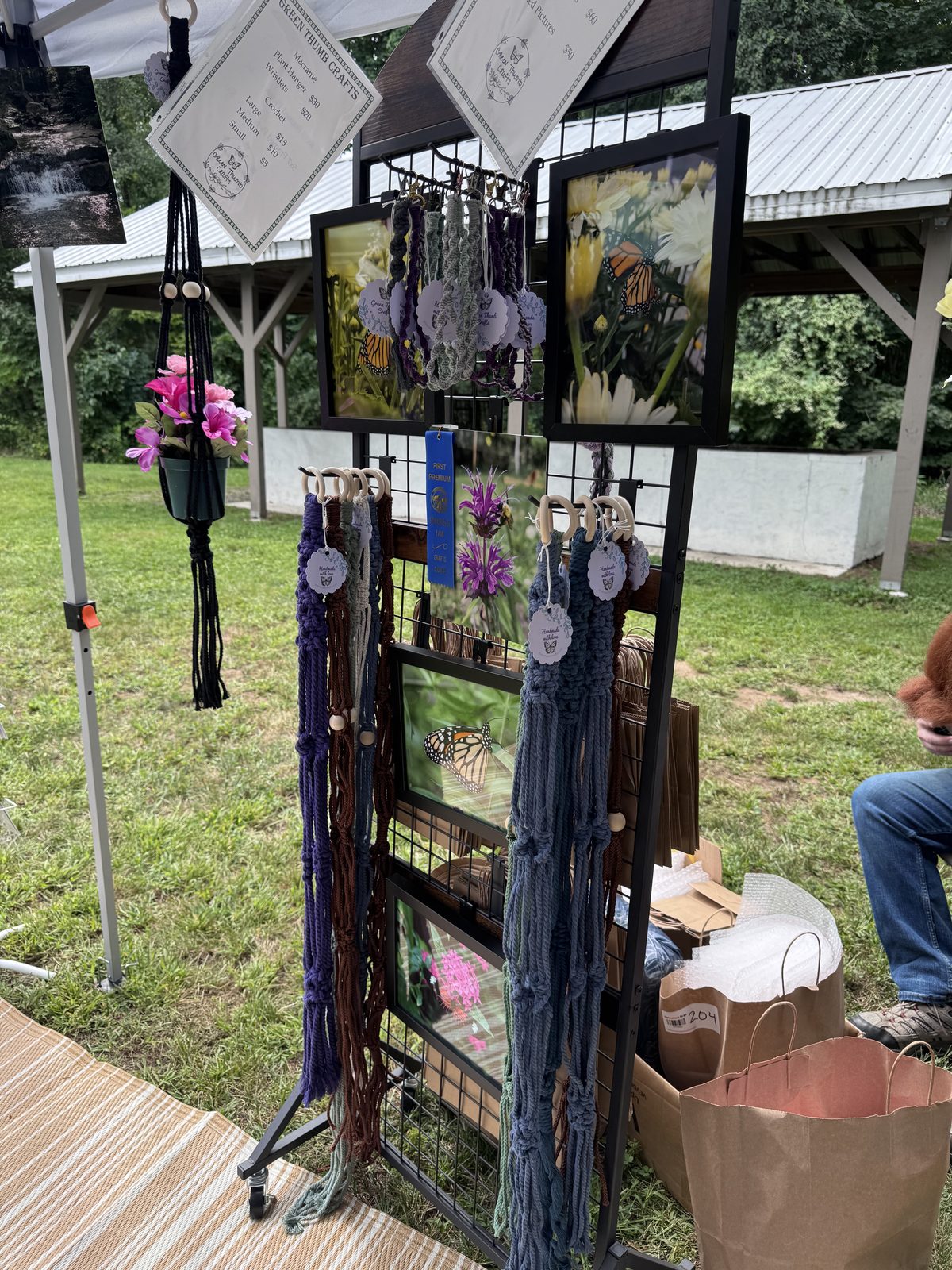 Vendor display of macrame plant hangers and butterfly photography