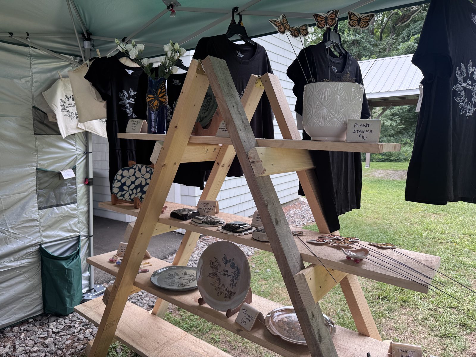Vendor tent with handmade pottery, t-shirts, and wooden display