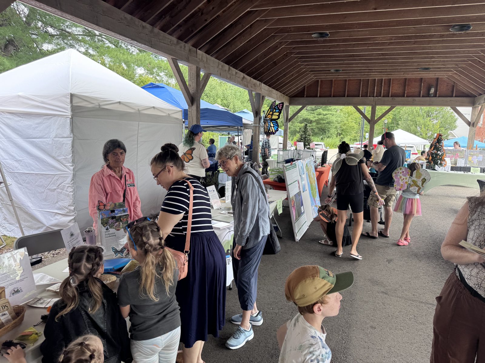 Visitors browsing informational displays under the pavilion